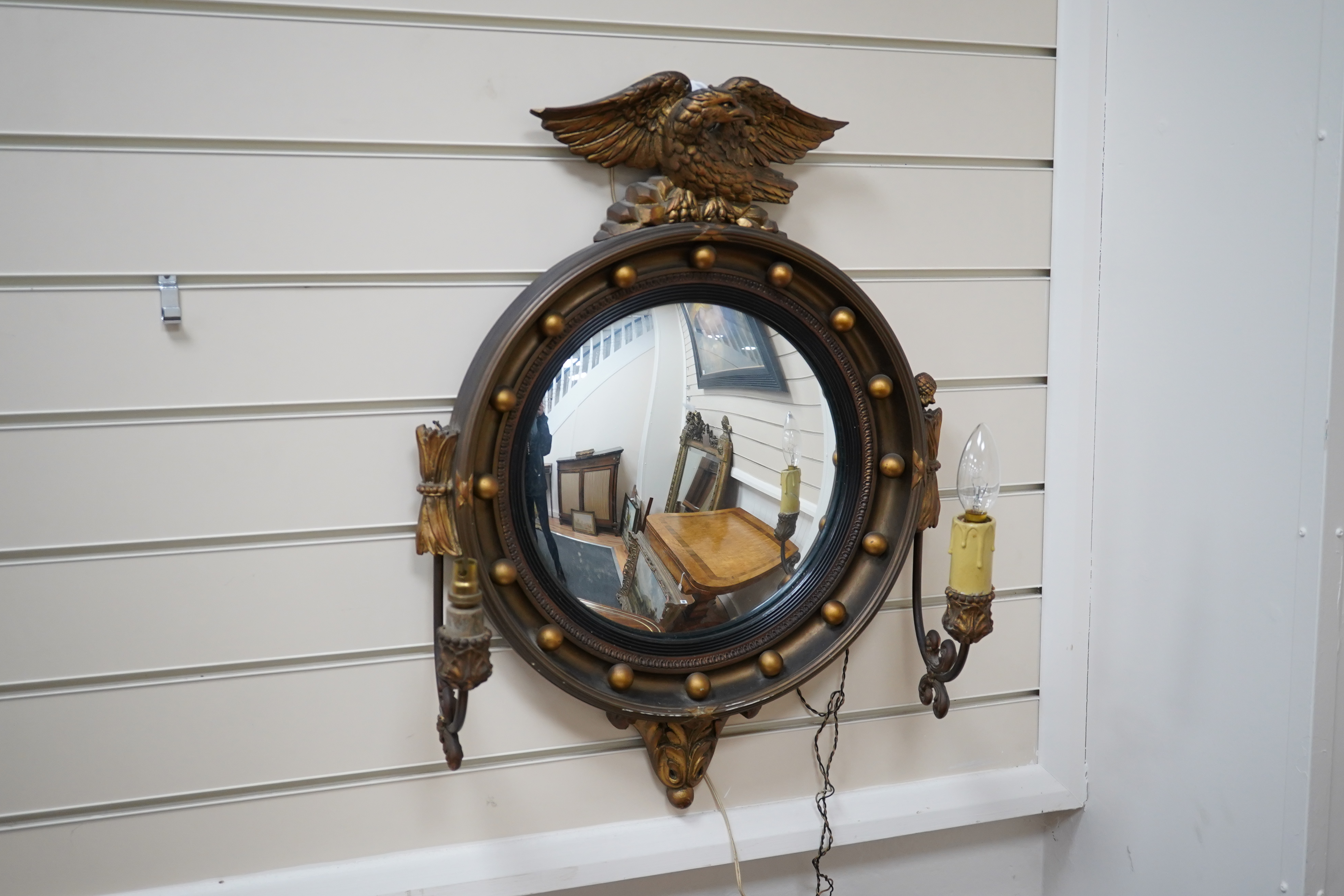 A circular convex gilt girandole mirror with carved eagle surmount, 62cm high. Condition - wing tip of eagle broken, gilt of frame scratched near the bottom, faux candle cover broken and the other missing